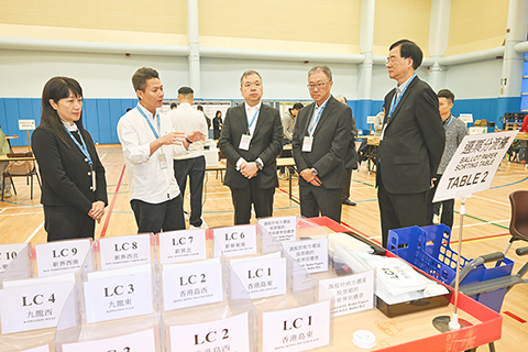 ◎ 十二月六日,香港選舉管理委員會主席陸啟康法官(右二)、委員石丹理教授(右一)和文本立資深大律師(中)下午到訪九龍公園體育館的選票分流站兼綜合大點票站,實地視察選舉工作人員的預備工作。旁為選舉事務處總選舉事務主任陳淑華(左一)。(香港中通社圖片)