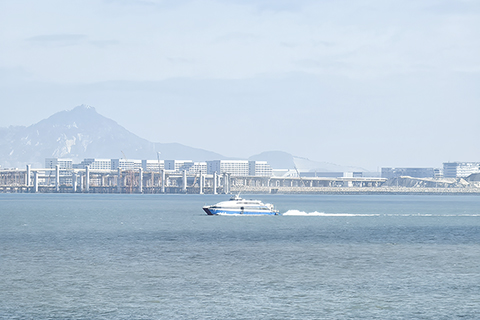 ◎ 二0二五年十二月廿七日,一艘經「小三通」航線的渡輪從廈門駛往大金門島,渡輪後方為正在建設的廈金大橋和廈門翔安國際機場。(中新社記者 劉大煒 攝)