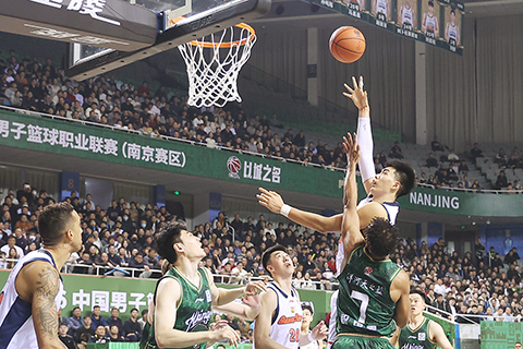 ◎ 一月十三日晚,CBA常規賽比賽中,廣東東陽光隊(白衣)客場八十七比七十一戰勝南京天之藍隊(綠衣)。圖為廣東東陽光隊球員焦泊喬投籃。(中新社記者 泱波 攝)