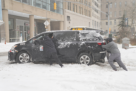 ◎ 一月二十五日,一場冬季風暴襲擊美國紐約,導致鐵路和渡輪服務減少,當地景區關閉,學校改為遠程上課。圖為當日,在美國紐約,人們推動陷在雪中的汽車。(新華社記者 張鳳國 攝)