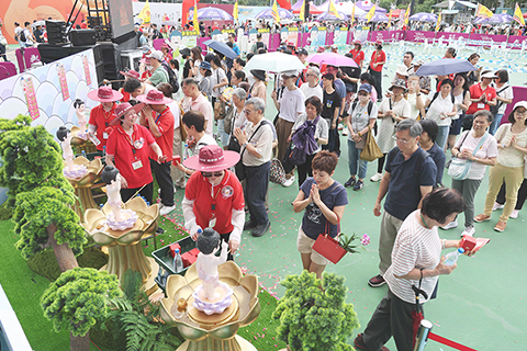 ◎ 五月廿四日,一年一度的佛誕嘉年華在維園舉行。維園佛誕嘉年華二零二六有過百個攤位,活動包括花果祈福、釋迦族巡遊、雲水書車、佛陀一生圖說、敲鐘許願。圖為市民參加公衆浴佛等洗滌心靈的活動。(香港中通社記者洪少葵 攝)