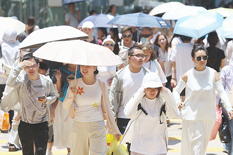 ◎ 八月九日,香港持續極端酷熱。天文台表示,受強颱風「白海豚」外圍下沉氣流影響,廣東普遍晴朗,香港昨日下午多處地區氣溫升至攝氏卅七度或以上。截至下午一時十五分,天文台總部錄得最高氣溫攝氏卅六點七度,打破自一八八四年有紀錄以來的最高氣溫紀錄。圖為外出的市民撐傘遮擋陽光。(香港中通社記者 陳奕啟 攝)